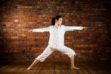 Girl exercising yoga against brick wall