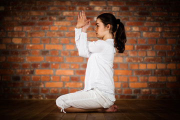 Woman exercising yoga against brick wall