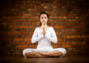 Woman exercising yoga against brick wall