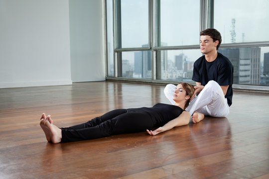 Instructor helping Woman In Yoga Exercise