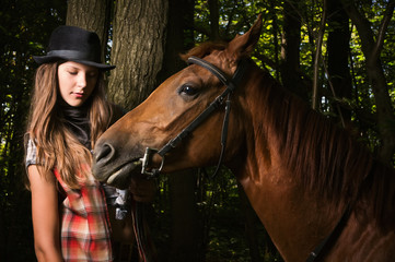 Cowgirl in hat with bay horse
