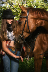 Obraz premium Cowgirl in hat with bay horse