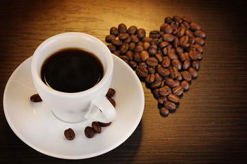 Cup of coffee on wooden table on brown background