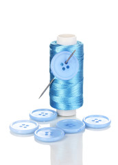 Blue bobbin with needle and buttons isolated on white