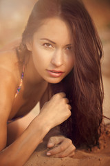 Fototapeta premium A beautiful girl in a bikini pours sand