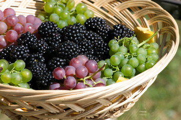 grapes and blackberries in a wooden basket on a glass table