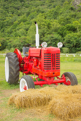 An old red retro tractor in a field