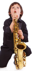 Fototapeta premium Portrait of handsome kid posing in studio with saxophone