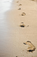 Foot prints at sand in summer sunrise on tropical beach