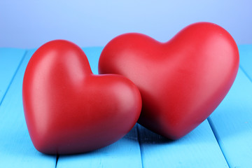 Decorative red hearts on blue wooden table on blue background