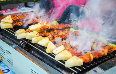 grilled bbq chicken and pork on a stick with peper and pineapple