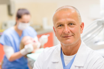 Mature dentist surgeon at office portrait