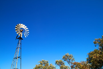 Windmill with blue sky and bush