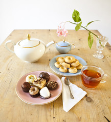 plates of pastries and biscuits and tea pot on wooden table