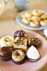 plates of pastries and biscuits and tea pot on wooden table