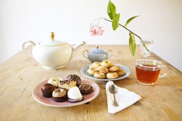plates of pastries and biscuits and tea pot on wooden table
