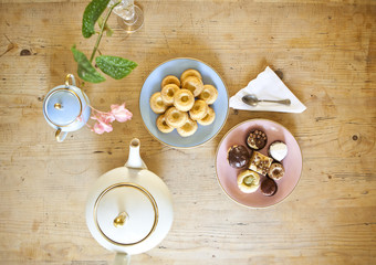 plates of pastries and biscuits and tea pot on wooden table