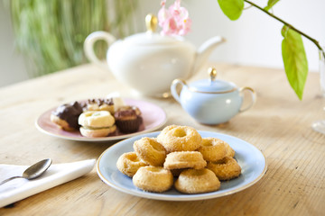 plates of pastries and biscuits and tea pot on wooden table