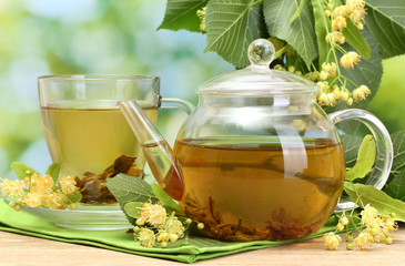 teapot and cup with linden tea and flowers