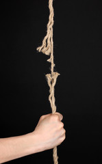 Breaking rope and hand isolated on black