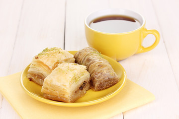 Sweet baklava on plate with tea on wooden background