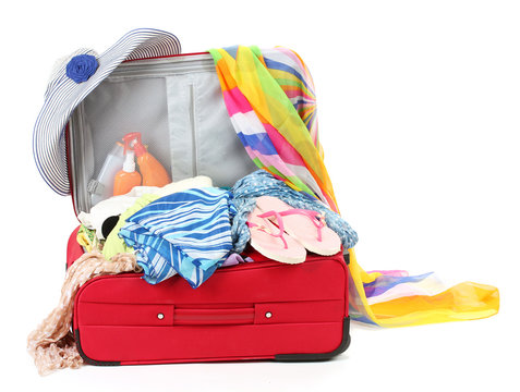 Suitcase with summer clothes, a hat and suntan isolated on