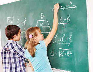 School child writting on blackboard.