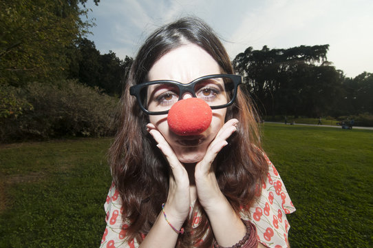 sad clown girl with red nose at the park