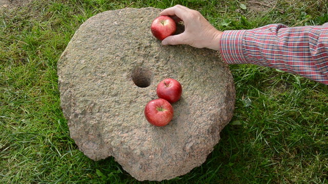 put three summer end red apples on historical millstone