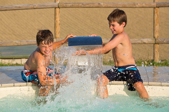 Zwei Jungen spritzen mit Wasser am Swimmingpool - Wasserschlacht
