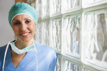 Nurse wearing surgical cap leaning against glass wall