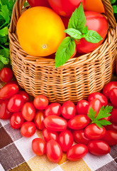 Wicker basket full of fresh tomatoes and cherry tomatoes