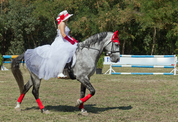 A woman in a white dress on a horse.
