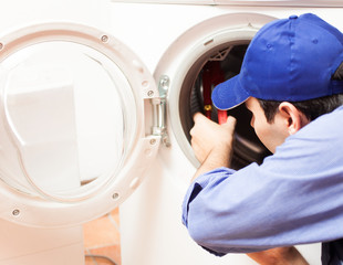 Technician repairing a washing machine - Powered by Adobe