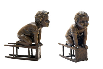 Antique bronze figurine depicting a boy sitting on a stool.