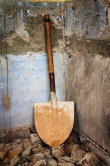 Dirty shovel in the corner of an old wall