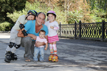 happy family - father and three children - on roller skates outd