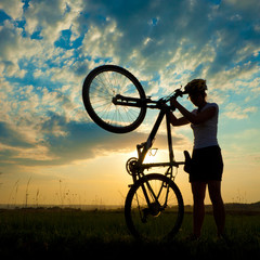 Biker-girl at the sunset on the meadow