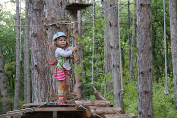young child girl in adventure park wearing mountain helmet and s