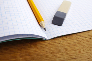 closeup of pencil notebook and eraser on wooden desk
