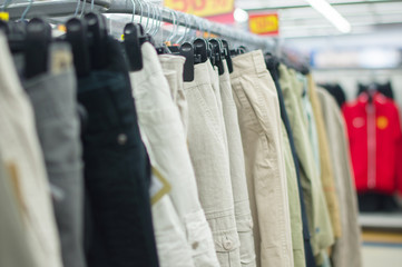 Variety of bright and dark trousers on stands in supermarket