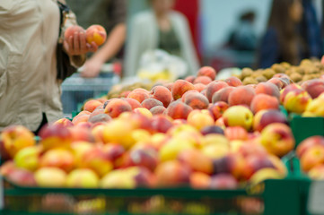 Customers selecting peaches in supermarket