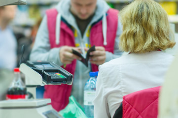 Cash-desk with cashier and terminal in supermarket. Serve custom