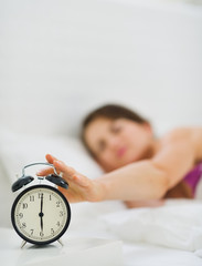 Closeup on female hand reaching to turn off alarm clock