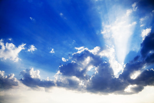 blue cloudy sky and bright sun beams