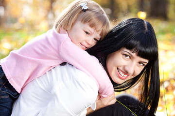 beautiful young mother and her daughter lying on the autumn leav