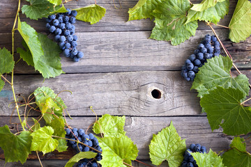 Grapes with green leaves on vintage wooden boards background - Powered by Adobe