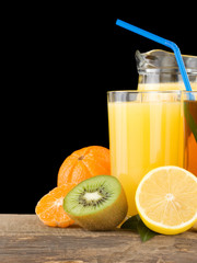 fresh fruits and juice in glass isolated on black