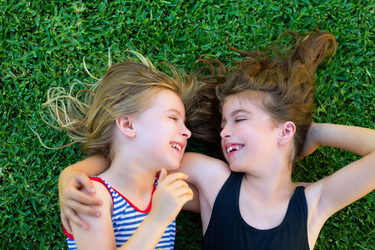 sisters kid girls smiling lying on garden grass