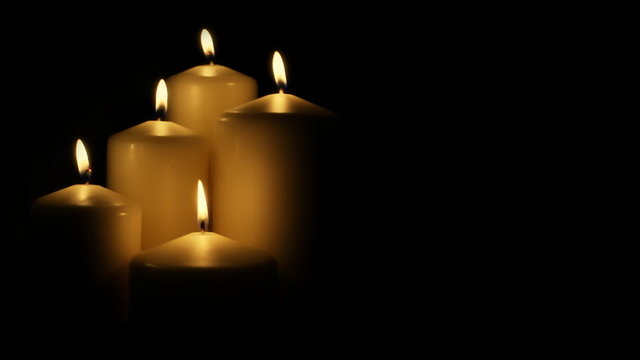 Five flickering candles on the black background